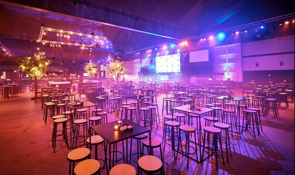 Feestzaal met statafels in paars en roze licht